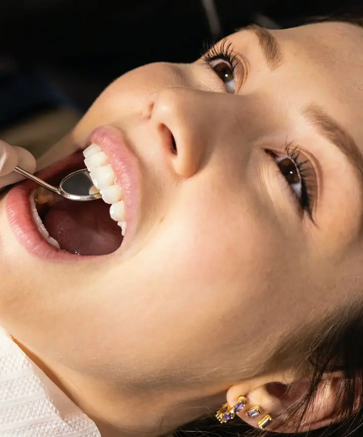 A patient receiving a dental examination, showing healthy white teeth