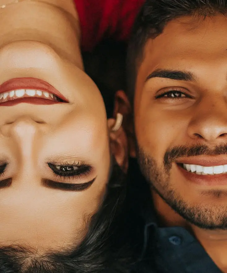 Two people smiling closely together, showing bright, healthy white teeth